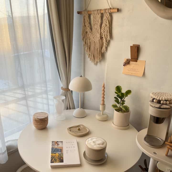 Natural style home cafe space in beige and white tones with a round table featuring a coffee cup and a book