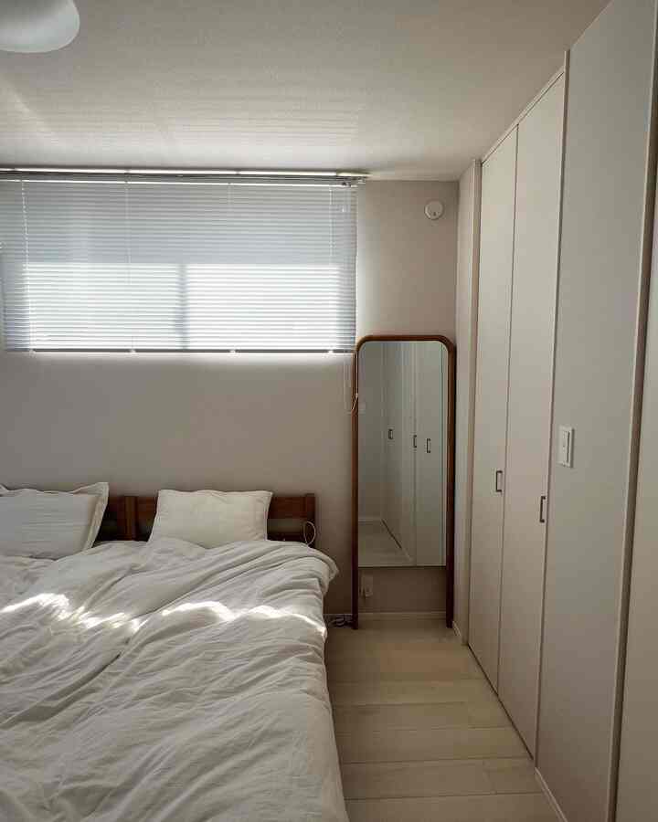 調和のとれたホワイトトーンの寝室、二つのシングルベッドと全身鏡が配置された清潔で落ち着いた空間