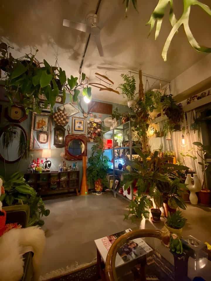 Warm brown tones and abundant green plants define this Showa Retro living room interior, with indirect lighting balancing density and atmosphere