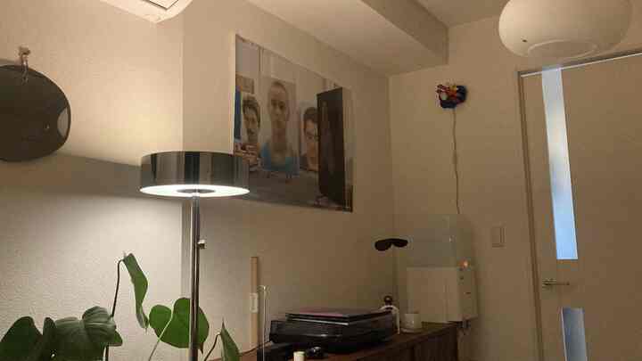 ナチュラルカラーの玄関、シルバーのフロアランプとポスターが配置された落ち着いた雰囲気のインテリア