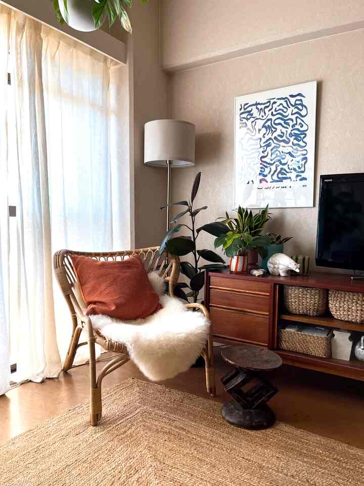 ナチュラルカラーのリビング、ラタンチェアとアフリカ風スツール、植物やフロアランプが配置された雰囲気のあるインテリア