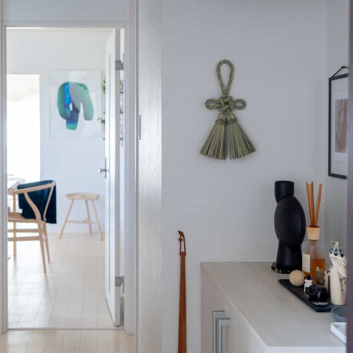 A bright and clean entrance with white and natural tones featuring wood-toned furniture and decor