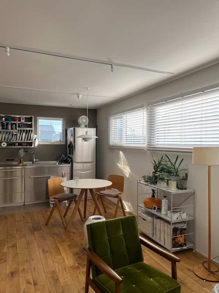 ホワイトとウッドトーンが調和したダイニングキッチン、HAYのテーブルとルイスポールセンの照明が配置されたモダンなインテリア