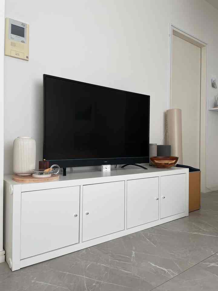 明るいホワイトトーンのリビング、低いテレビ台とテレビ、木製の小物が調和した清潔感のあるインテリア