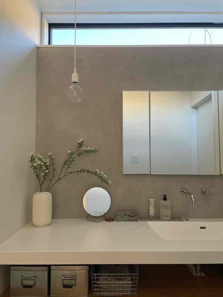 Bright white and beige toned bathroom featuring a ceramic vase with spirea branches, showcasing a minimal and clean design