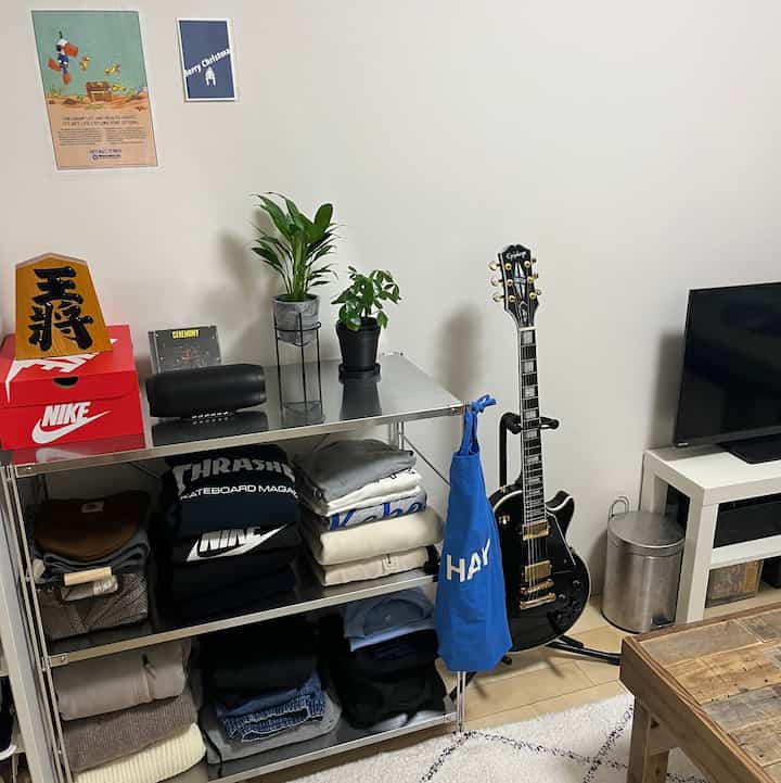 白い壁とステンレス棚、黒いギターが配置された高校生の男の子のきれいな部屋