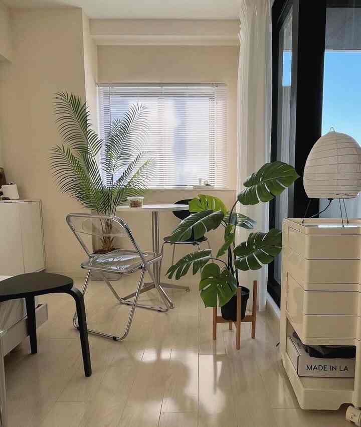 A natural color tone small dining space featuring a round table and clear chair, creating a cozy interior atmosphere