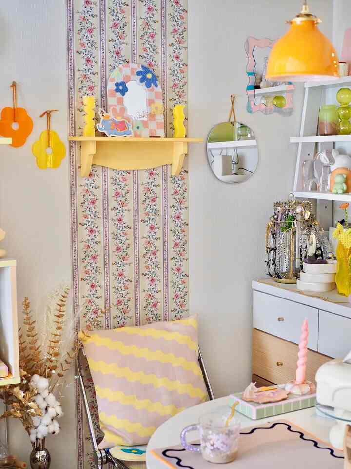 白と黄色のトーンのリビングコーナー、多彩な棚とペンダントライトが配置された印象的な空間