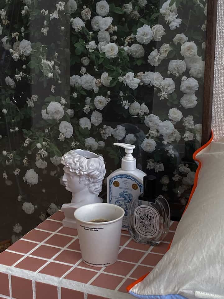 Mid-Century Modern bedroom with a pink tile table displaying white decorative objects and a coffee cup, creating a cozy atmosphere