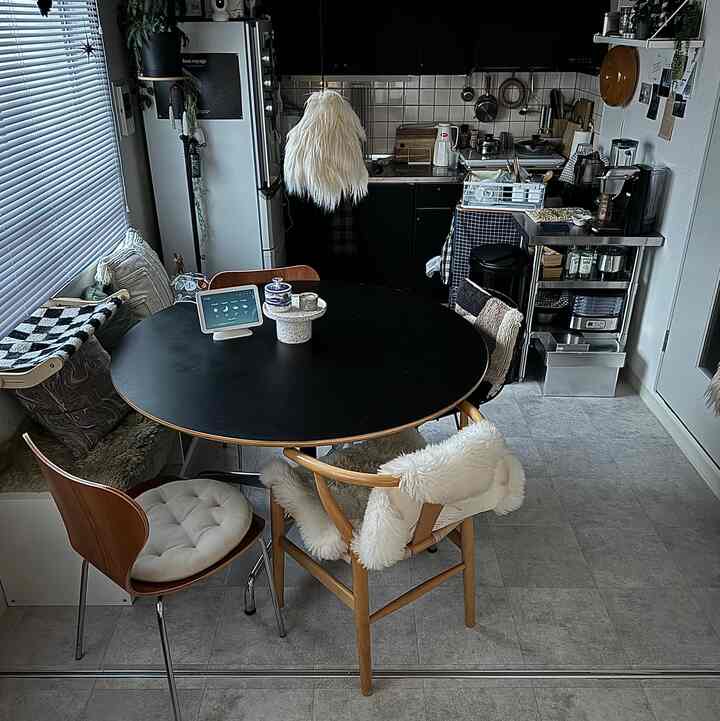 Black and wood tone dining room featuring a simple round dining table and chairs in a cozy single household kitchen space