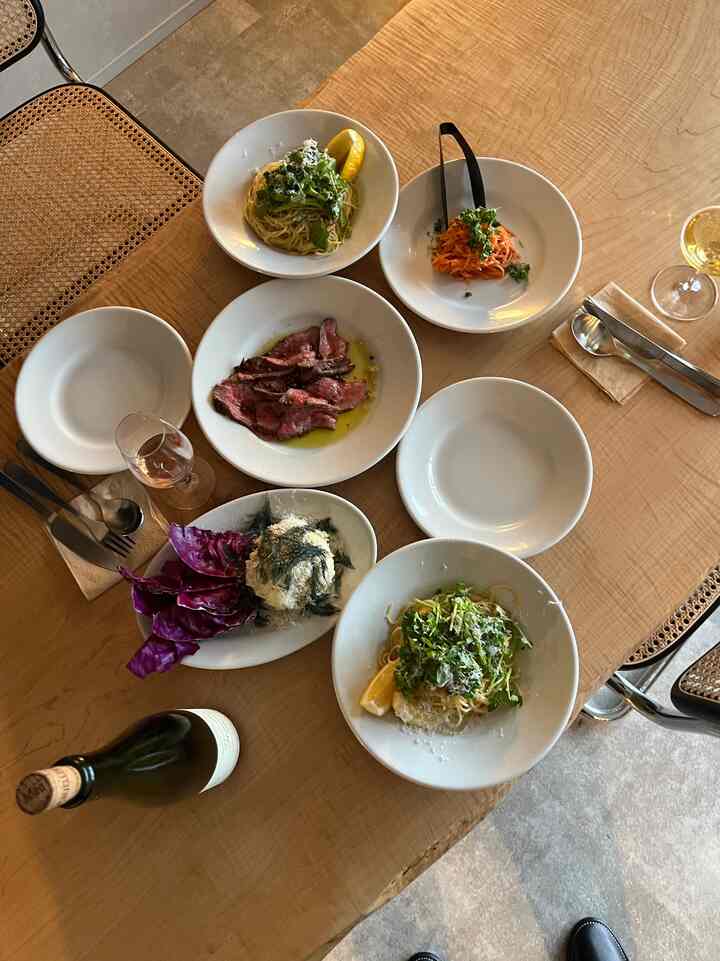 温かみのある茶色い木製ダイニングテーブルに白い皿とワイングラスが置かれた、雰囲気のあるダイニングルーム