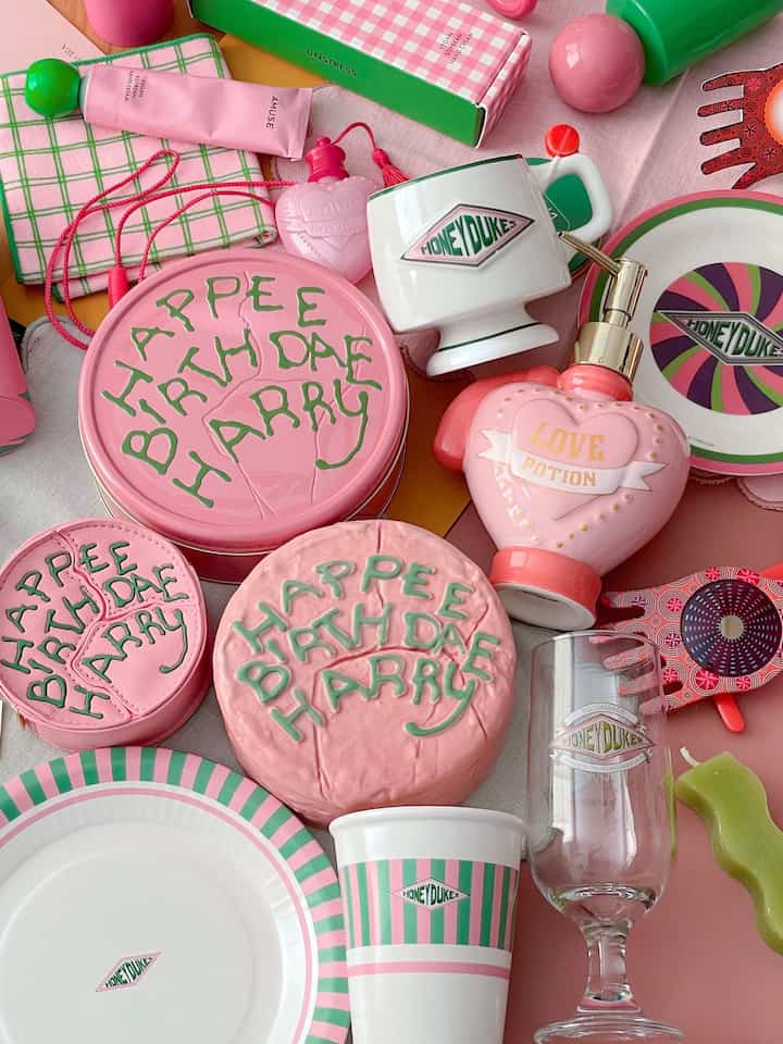 Colorful Harry Potter-themed items in dominant pink and green tones, featuring plates and cups arranged as charming decorative pieces