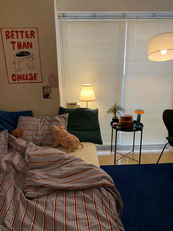 白とネイビーの色調の寝室、快適なベッドとナイトテーブルの上にランプと植物が配置された雰囲気のある空間