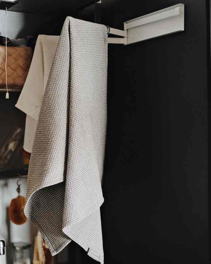 黒い背景にベージュのキッチンタオルが掛けられたシンプルでモダンなキッチンタオルの空間