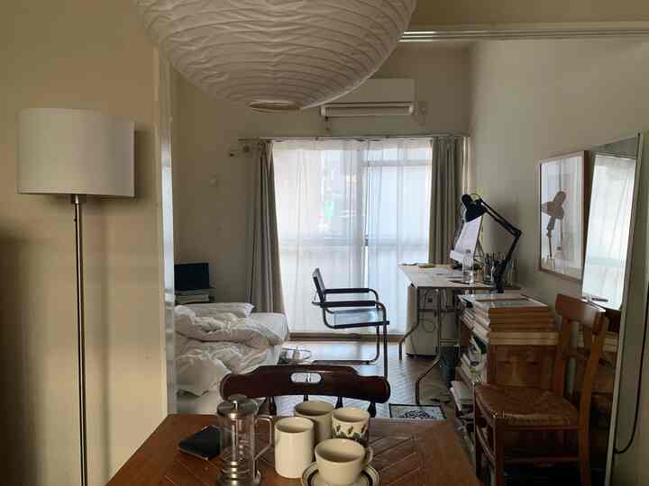 ナチュラルな色調の9畳アパルトマン、ソファベッドやデスク、照明が配置された落ち着いた雰囲気のインテリア