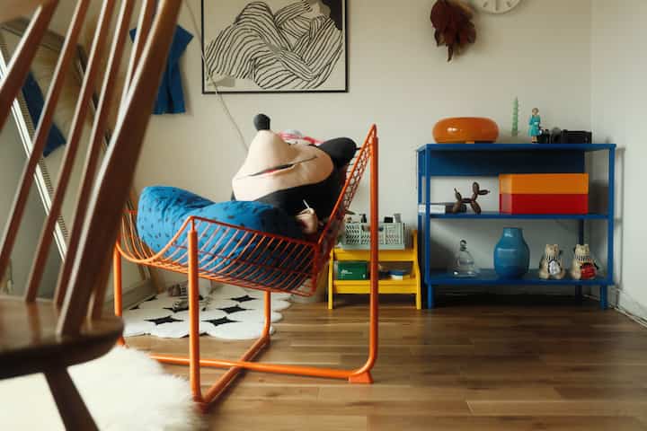 明るい木目調の床、オレンジのスツールと青い棚が配置された子供部屋のインテリア