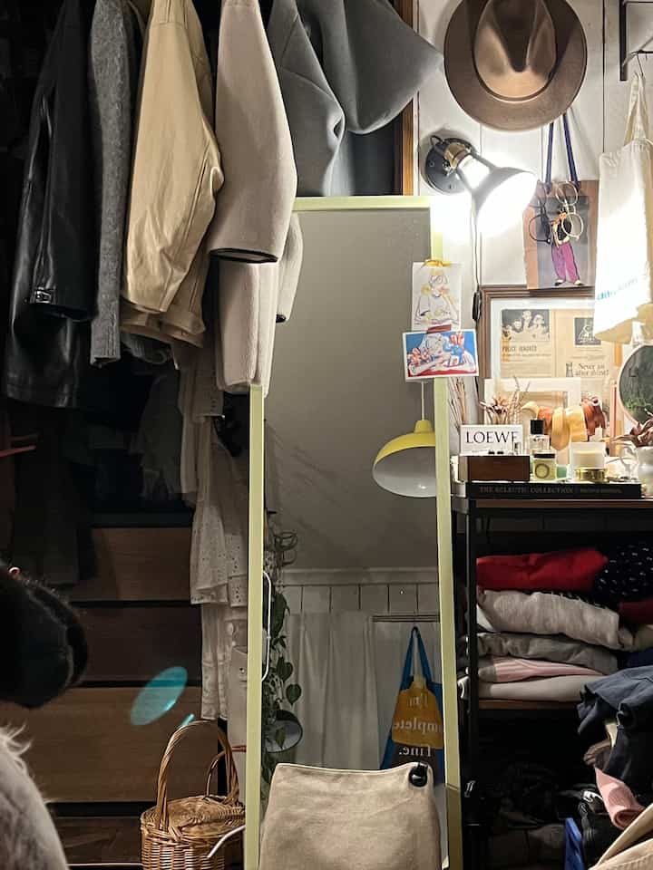 ベージュと黒のトーンが調和した狭い空間、全身鏡とワードローブが配置された実用的な収納スペース