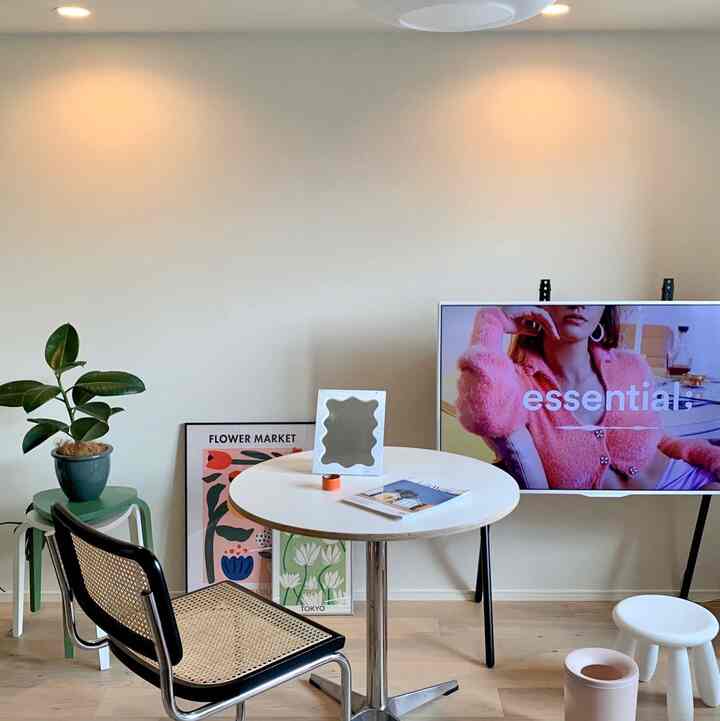 白とナチュラルカラーが調和したミッドセンチュリーモダンのリビング、丸いダイニングテーブルとテレビ台、スツールが配置されたシンプルな空間