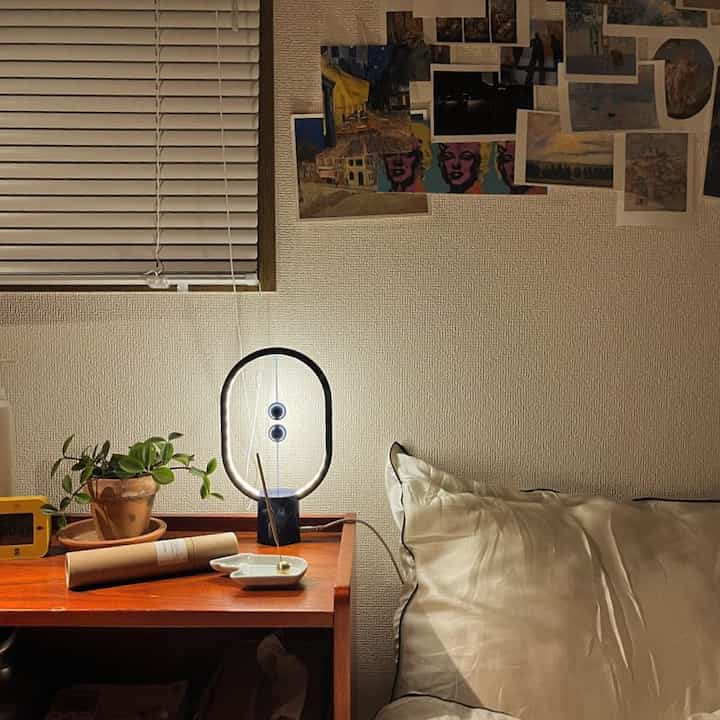 ナチュラルトーンの木目調が特徴の8畳寝室、温かみのある照明と植物、線香が配置された雰囲気のあるインテリア