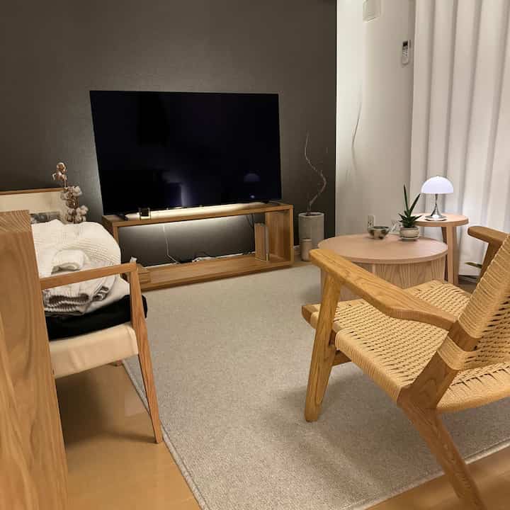 Wood tone and beige studio apartment living room featuring simple natural coffee table and chairs creating a cozy atmosphere