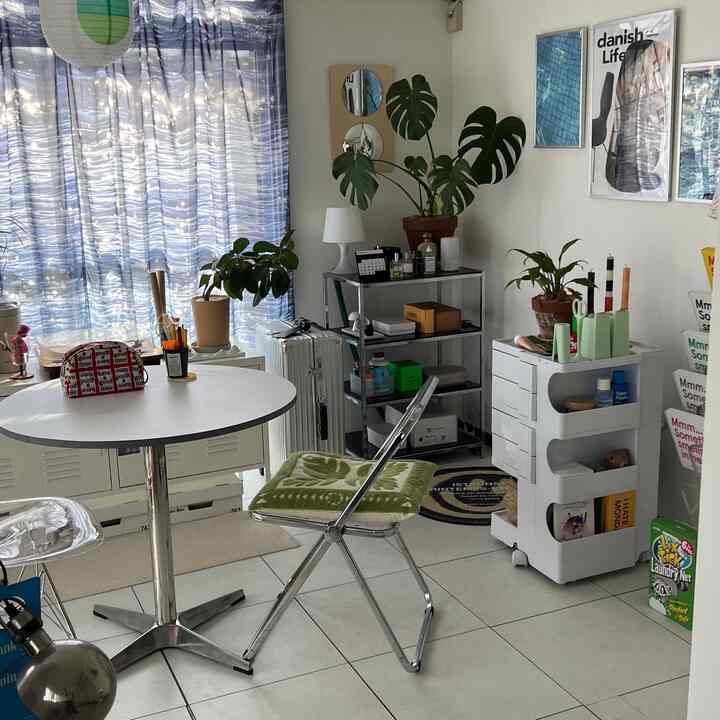 白とナチュラルグリーンのトーンの小さな一人暮らし空間、ダイニングテーブルと植物が配置されたミニマルなインテリア