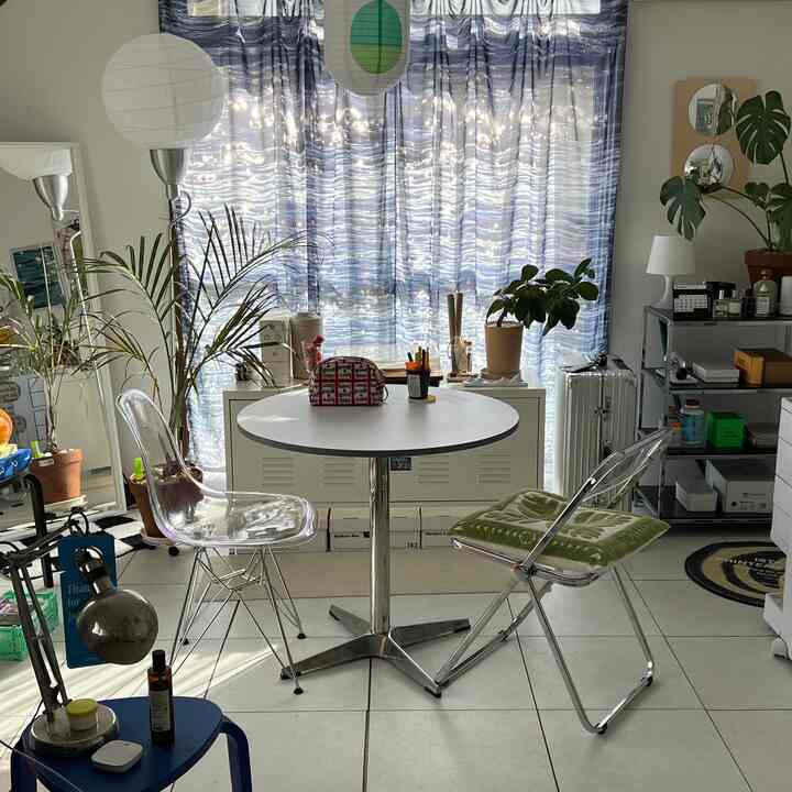 白と青のトーンのワンルーム、透明のダイニングチェアと丸いテーブルが配置された清潔感のあるモダンなインテリア