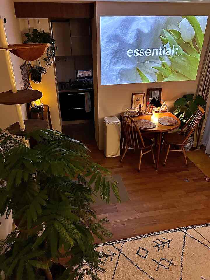 暖かい木目調のリビングとダイニング、ヴィンテージの食卓と椅子、プロジェクタースクリーンが配置された落ち着いた雰囲気のインテリア