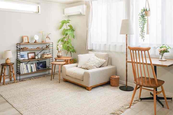 A cozy study in beige and wood tones featuring a single armchair sofa, bookshelf, floor lamp, and plants creating a natural atmosphere