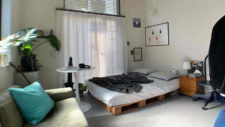 Bright, minimalist bedroom featuring a pallet bed and green sofa creating a cozy atmosphere