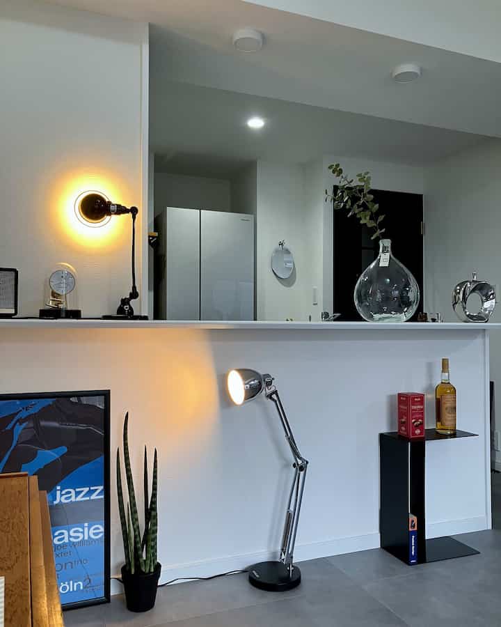 White-walled kitchen interior featuring industrial metal table lamps and a black side table in a modern, clean space
