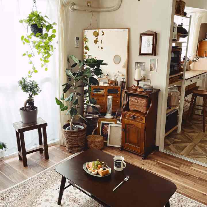 ナチュラルな木目調のリビング、多様な植物とヴィンテージ家具が調和した温かみのある空間