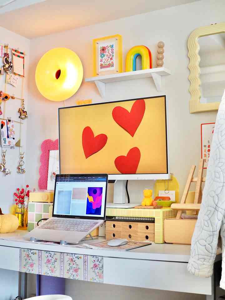 黄色と白のトーンのホームオフィス、ホワイトデスクにノートパソコンとモニターが配置された明るく温かみのある作業空間