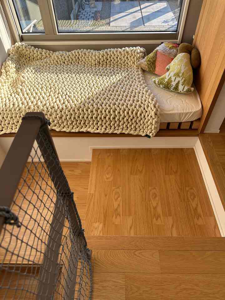 Natural wood-tone bedroom featuring cozy pillows and a chunky knit blanket with a warm atmosphere