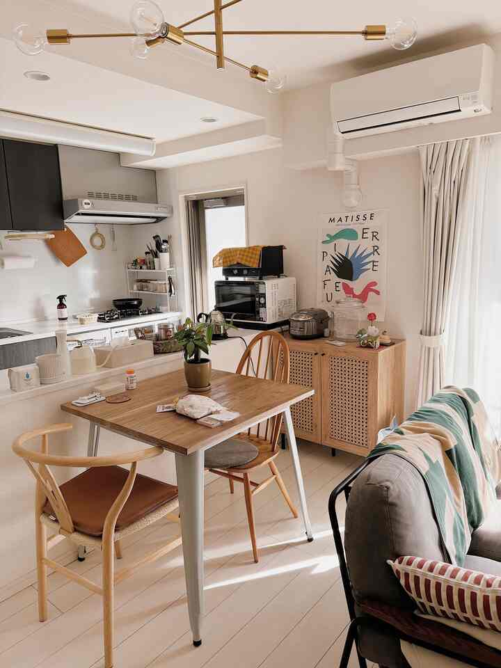 Bright white and natural brown toned living room and kitchen featuring wooden dining table and chairs with a warm, clean atmosphere