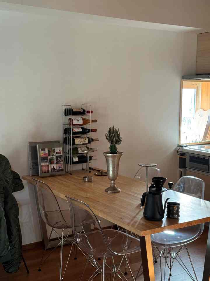 白い壁と木目調のテーブルがあるシンプルなダイニング、透明な椅子が配置され落ち着いたおうちカフェの雰囲気を演出