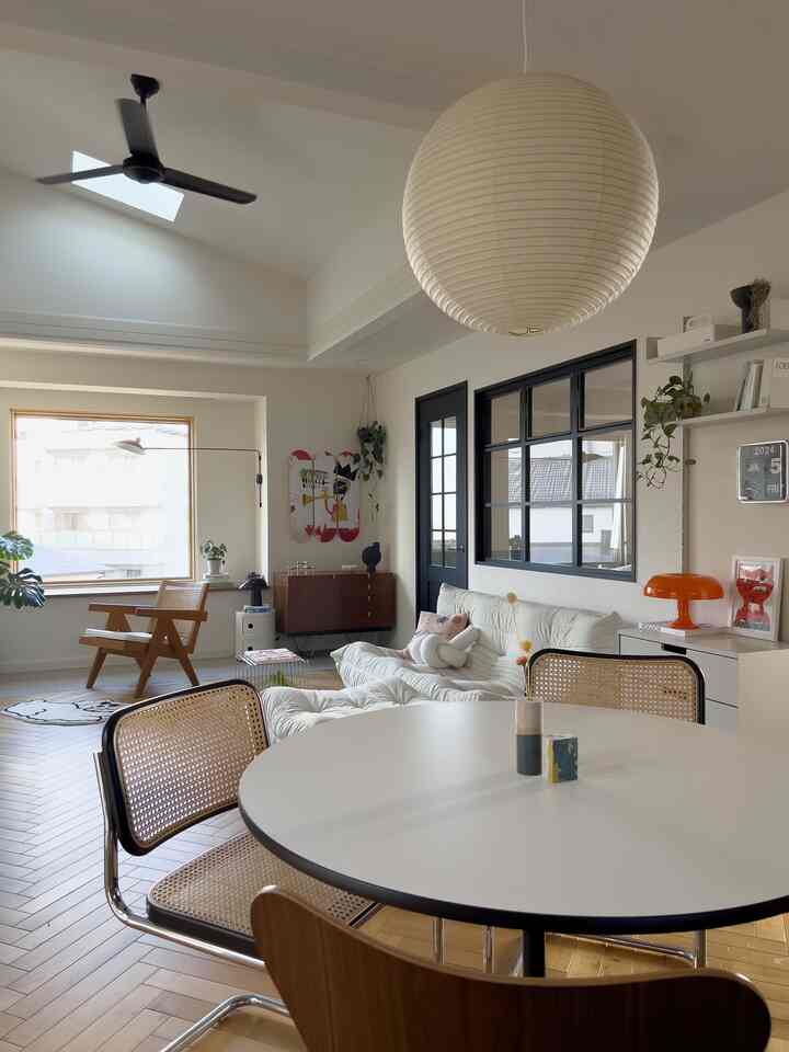 白と木目調のナチュラルモダンなダイニングとリビングの空間、大きなペンダントライトが中央に配置された雰囲気のあるインテリア