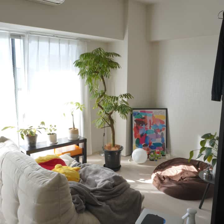 ナチュラルなホワイトと木目調のリビング、ソファやビーンバッグ、観葉植物が配置された雰囲気のあるインテリア