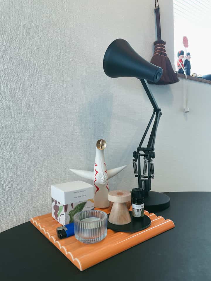 黒いテーブルにベージュのトレイと木製のオブジェが配置されたナチュラルな雰囲気のワークスペース