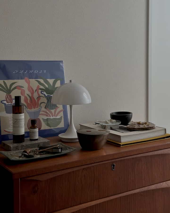 ナチュラルなブラウンの木目調玄関の棚に白いテーブルランプと小物が配置されたヴィンテージ風の雰囲気のあるインテリア