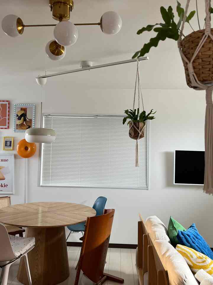 白と木目調が調和したダイニング、丸い食卓とカラフルなクッションが配置された雰囲気のある空間