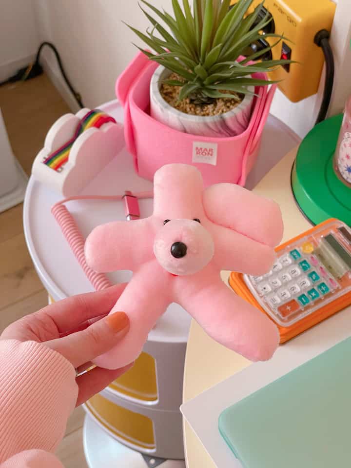 Bright pink dog plush on a white round desk in a charming, retro-inspired workspace