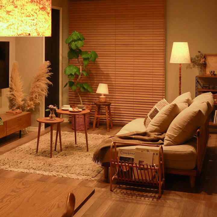 暖かい木目調とナチュラルな素材が調和したリビング、3人掛けソファと間接照明が落ち着いた雰囲気を醸し出す空間