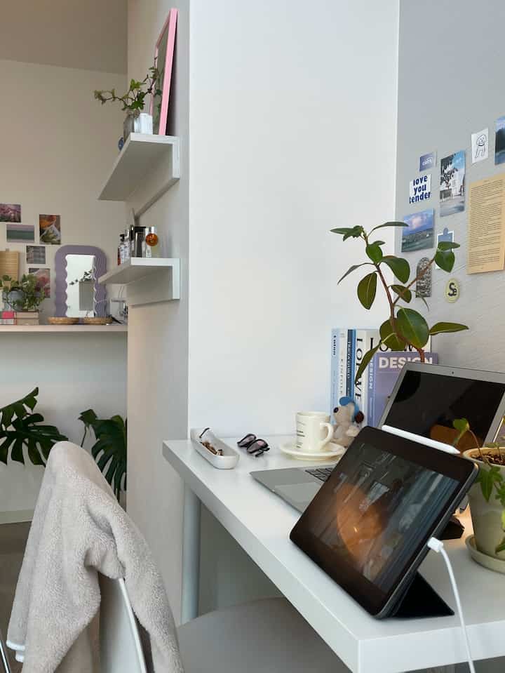 White and natural color toned home office space featuring desk with laptop and plants, creating a clean and cozy atmosphere