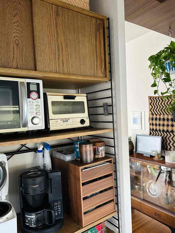 ナチュラルな木目調の狭いキッチン、コーヒーメーカーと木製収納が配置されたヴィンテージ感のあるインテリア