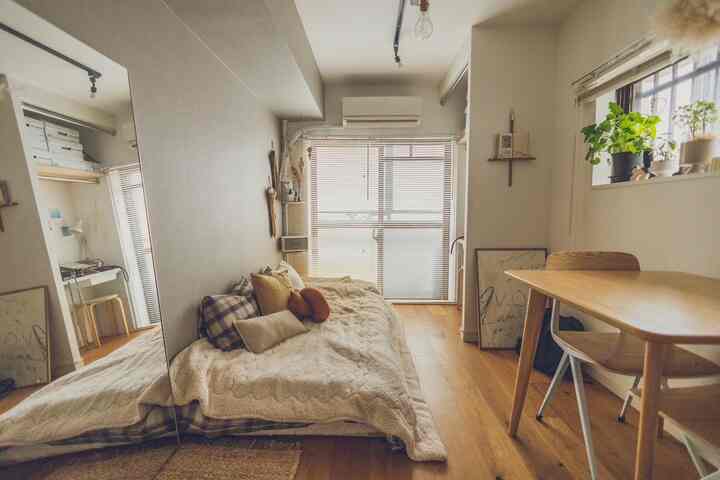 暖かいナチュラルカラーの8畳寝室、快適なベッドと窓のブラインド、窓際の植物が配置された雰囲気のある空間