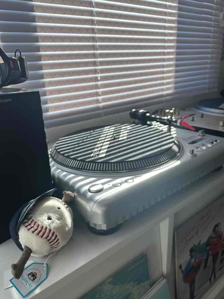 白いブラインドとシルバーのDJターンテーブルが配置されたゲームルームの雰囲気ある空間