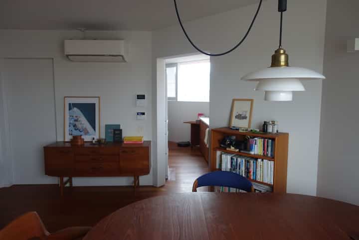 ナチュラルな木目調と白い壁が調和するダイニングルーム、ミッドセンチュリーモダンの家具が配置された落ち着いた雰囲気のインテリア