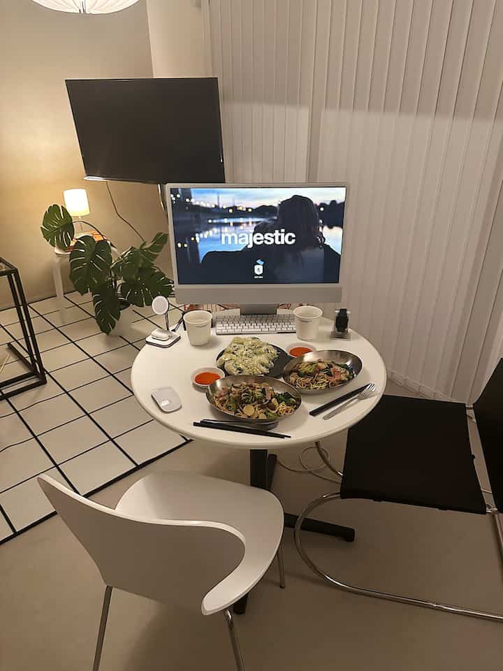 白黒を基調としたコンパクトな部屋、丸いダイニングテーブルに2脚の椅子とパソコンモニターが配置された雰囲気のあるホームオフィス空間