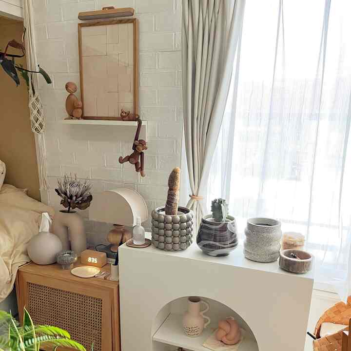 Bright natural-toned living room with various potted plants and curtains by the window creating a peaceful atmosphere