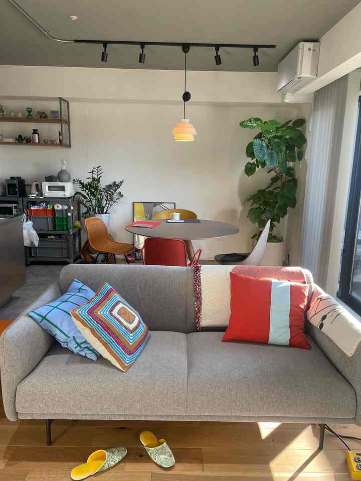 Natural tone living and dining room featuring a gray sofa, round dining table, and colorful cushions with a cozy atmosphere